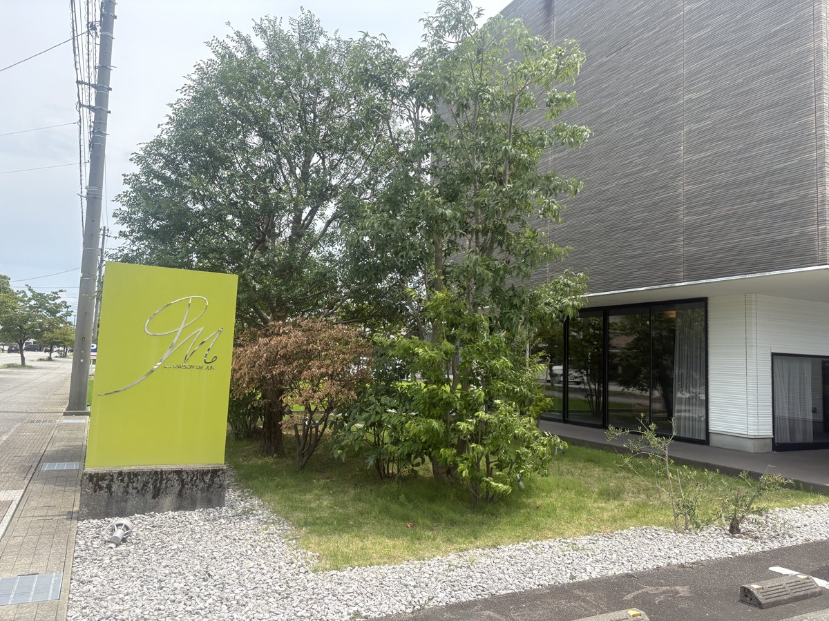 メゾンドジュン(富山市)の外観と黄緑のロゴ看板