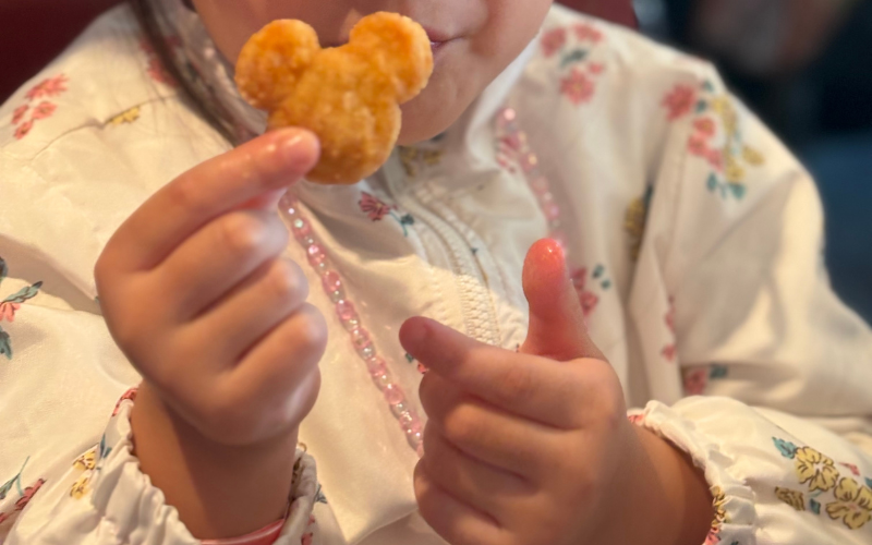 ミッキー型のナゲットを持つ子どもの手