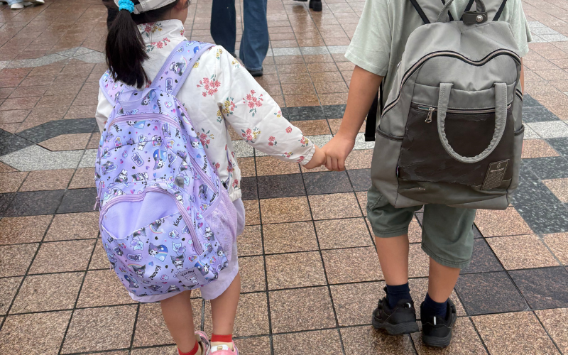 手をつないで歩く子どもたちの後ろ姿